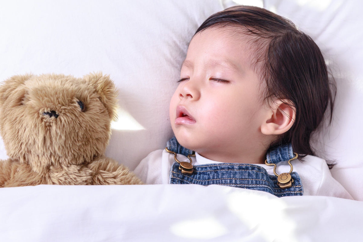 Baby girl on her back sleeping on a Baby's First Organic Sustainable Pillow by A Little Pillow Company