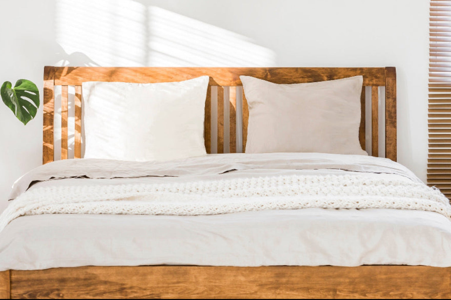 Bed with standard pillows from A Little Pillow Company in a bright room with plants