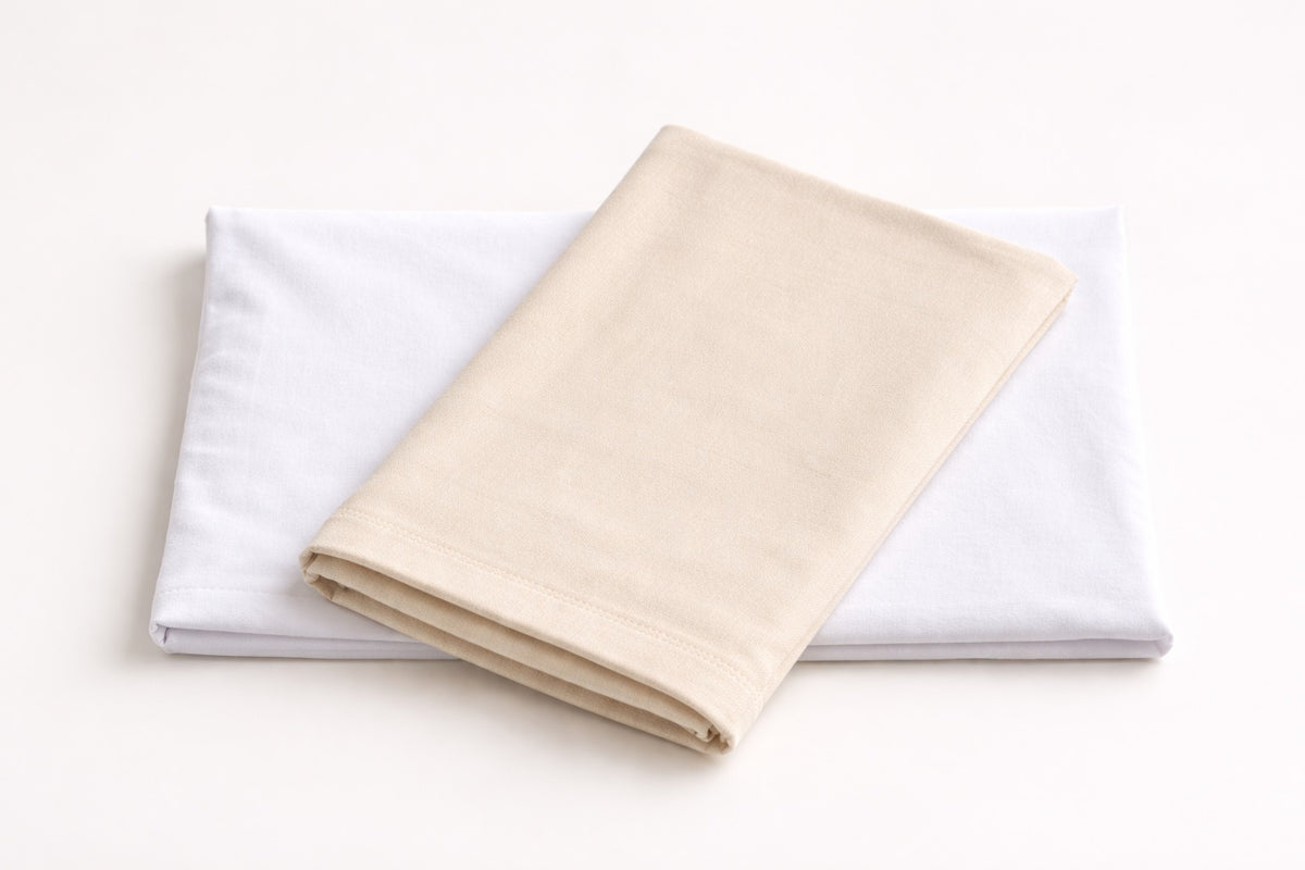 Two folded organic cotton pillowcases in natural beige and white, made in the USA by A Little Pillow Company and available in sizes for toddlers, kids, teens, and adults.